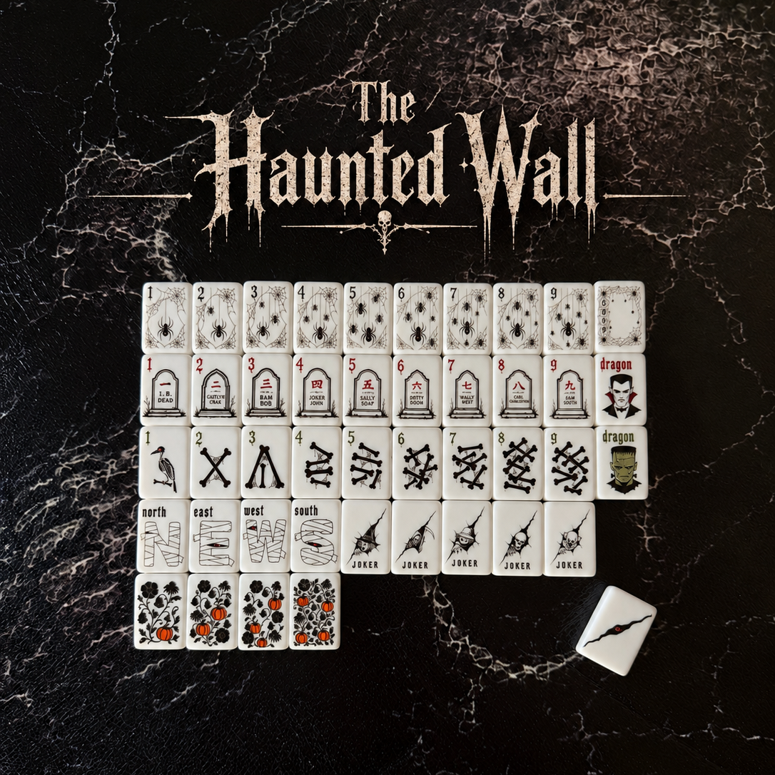 A set of themed playing cards arranged in rows on a dark marbled surface, with the title 'The Haunted Wall' printed above. A small white dice cube sits to the lower right.