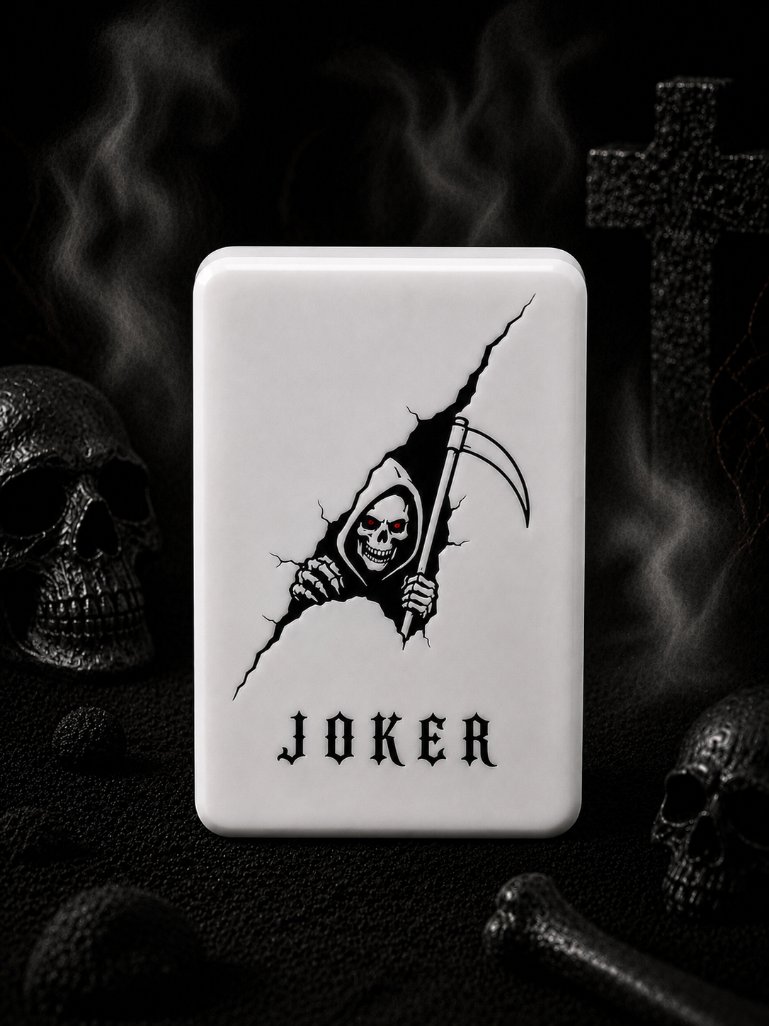 A white mahjong tile with rounded corners featuring a black graphic of a grim reaper tearing through the surface and the word 'JOKER' below, set against a dark gothic background with skulls and smoke.